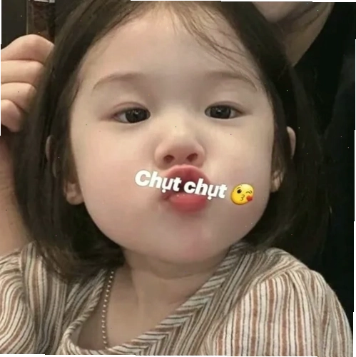 Em bé má phúng phính tóc ngắn đang phồng má chu môi giận dỗi khi đang ăn, tạo nên một biểu cảm ngộ nghĩnh