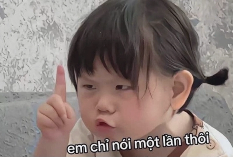 Em bé với vẻ mặt hơi buồn nhưng vẫn cố gắng tỏ ra mạnh mẽ