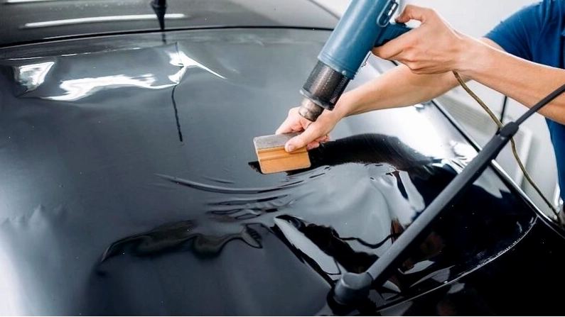 Kỹ thuật viên gạt bỏ bọt khí sau khi dán phim cách nhiệt