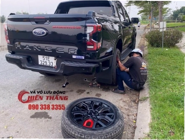 Người lái xe đang kiểm tra lốp xe bị xì hơi trên đường