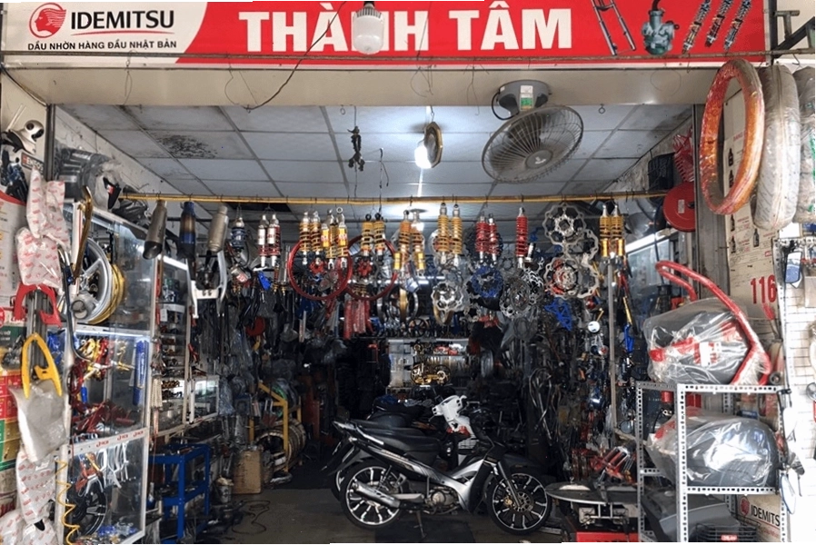 Thợ sửa xe máy đang kiểm tra bộ phận động cơ tại quán sửa xe máy gần đây